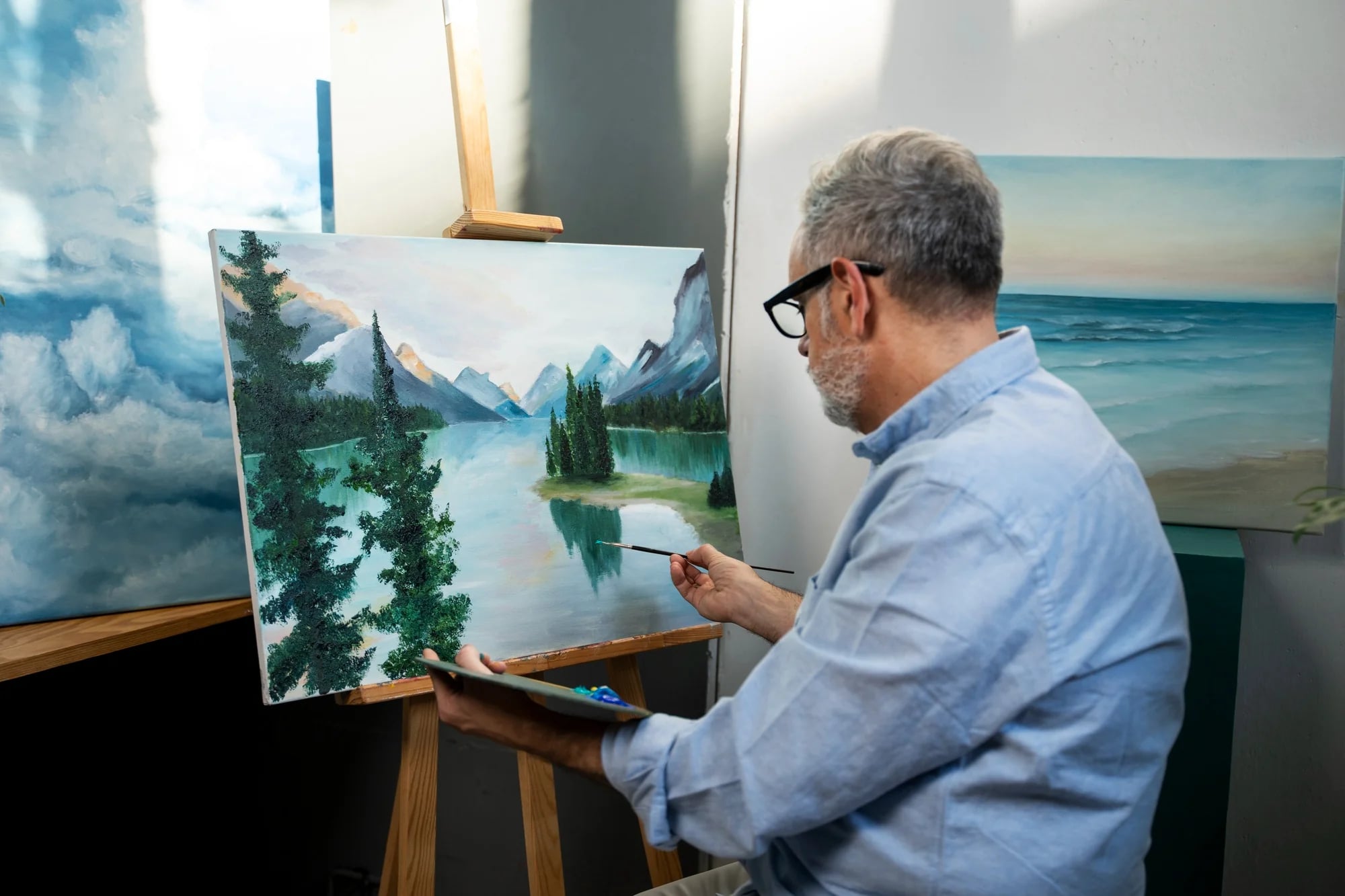 Homem pintando uma paisagem de montanhas em um cavalete