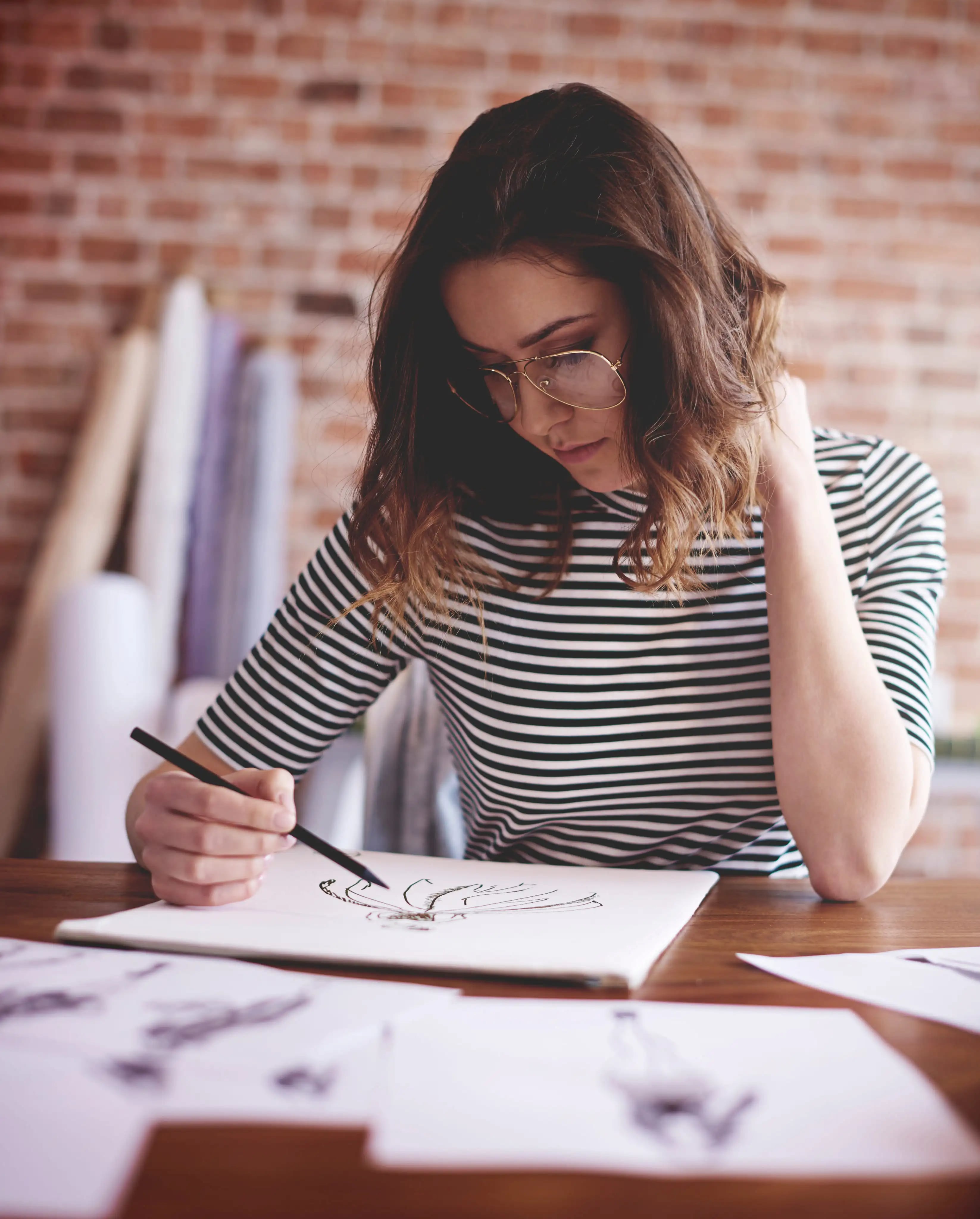 Mulher de óculos desenhando a lápis em um caderno de esboços