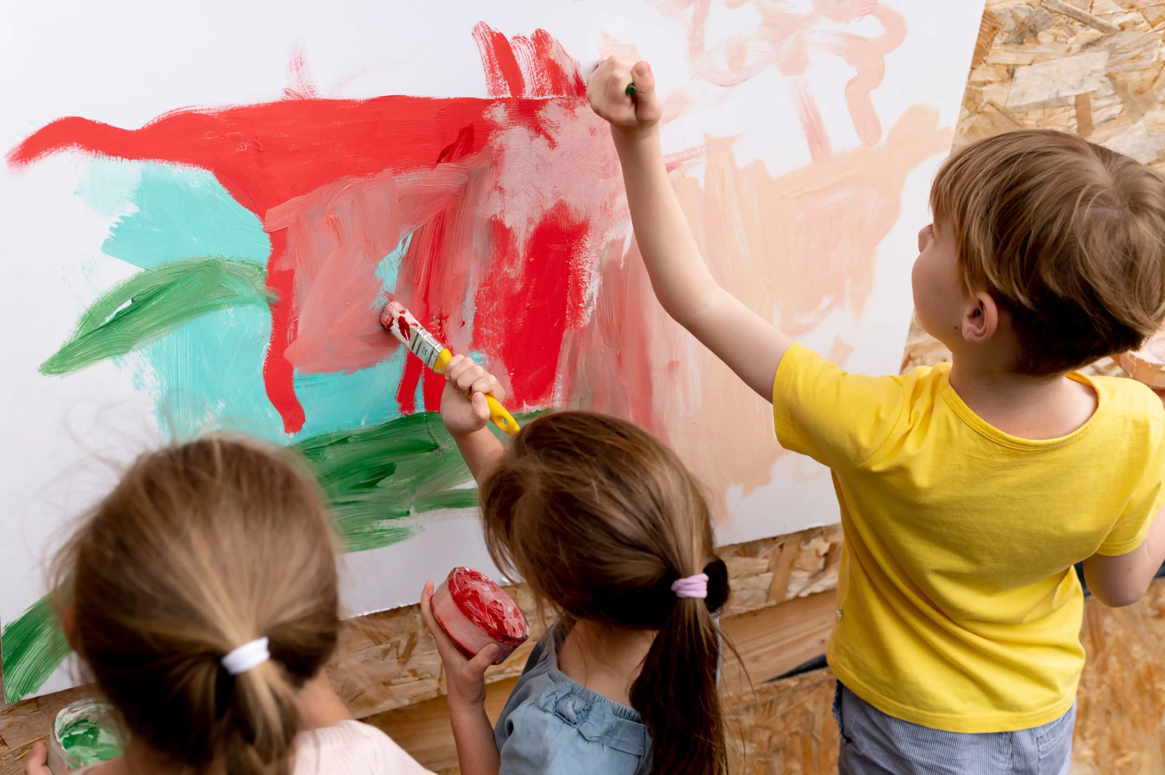 Crianças pintando juntas em ambiente de aula colaborativa