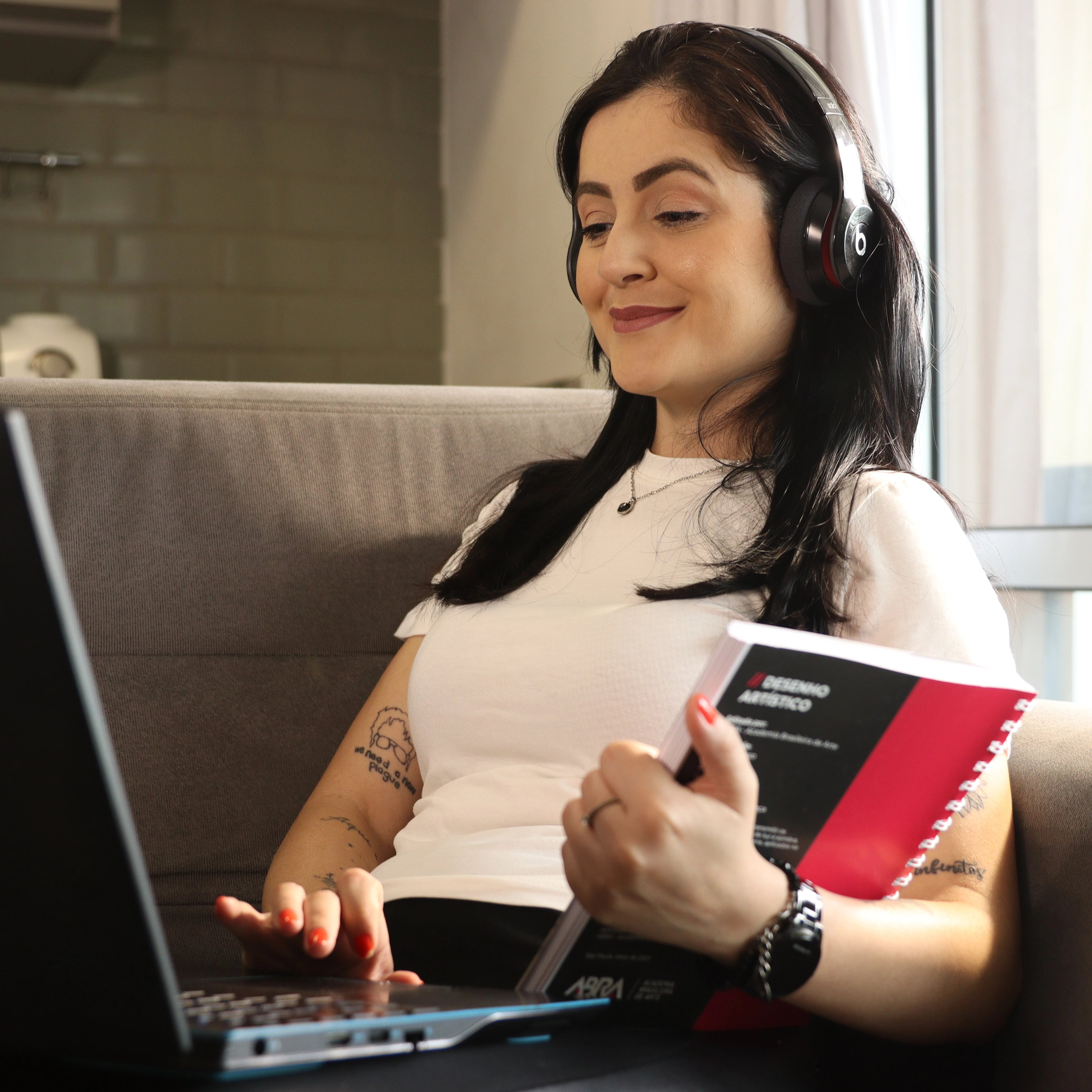 mulher com apostila da abra estudando em casa com seu laptop