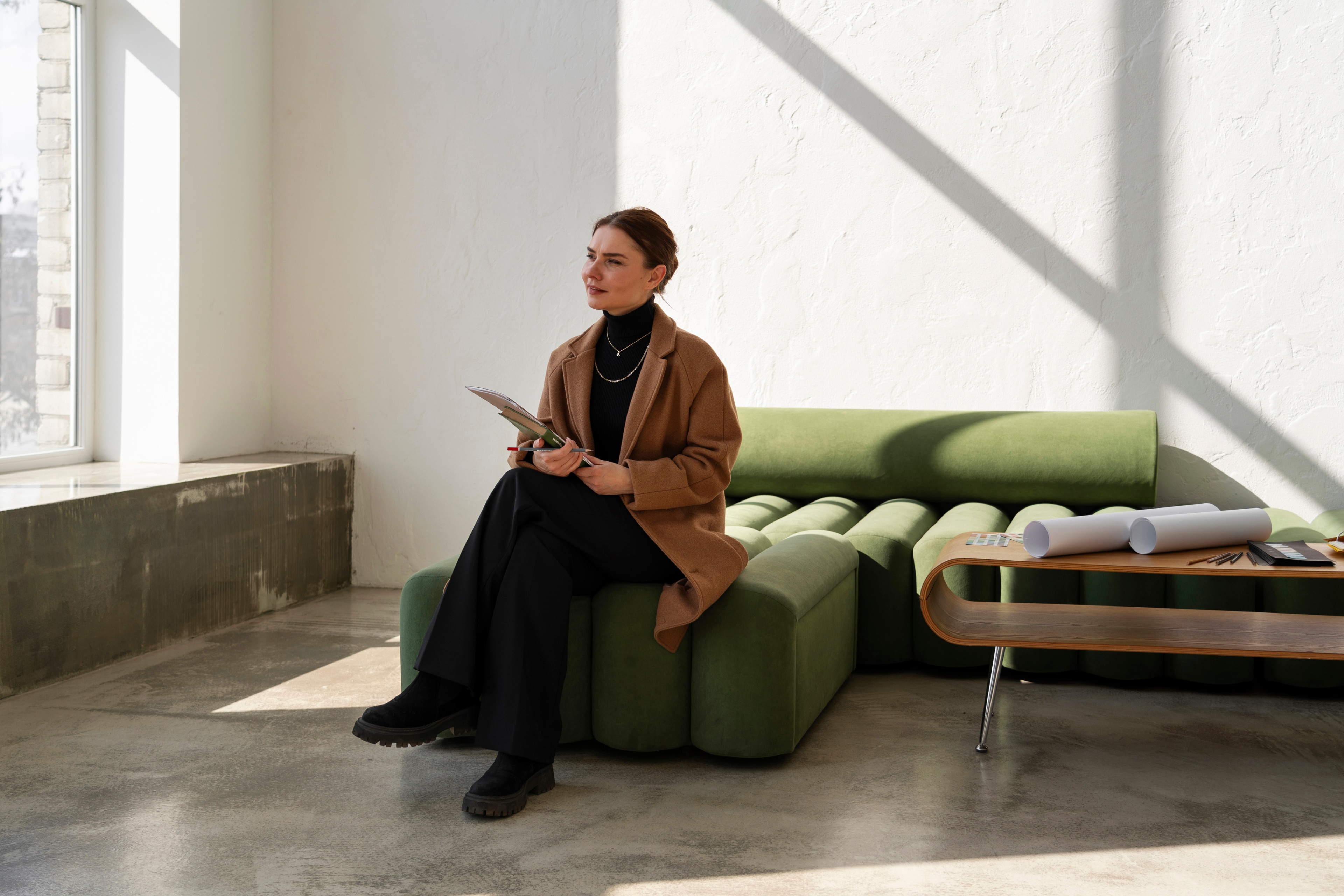 mulher de sobretudo marrom com materiais de designer de interiores.webp
